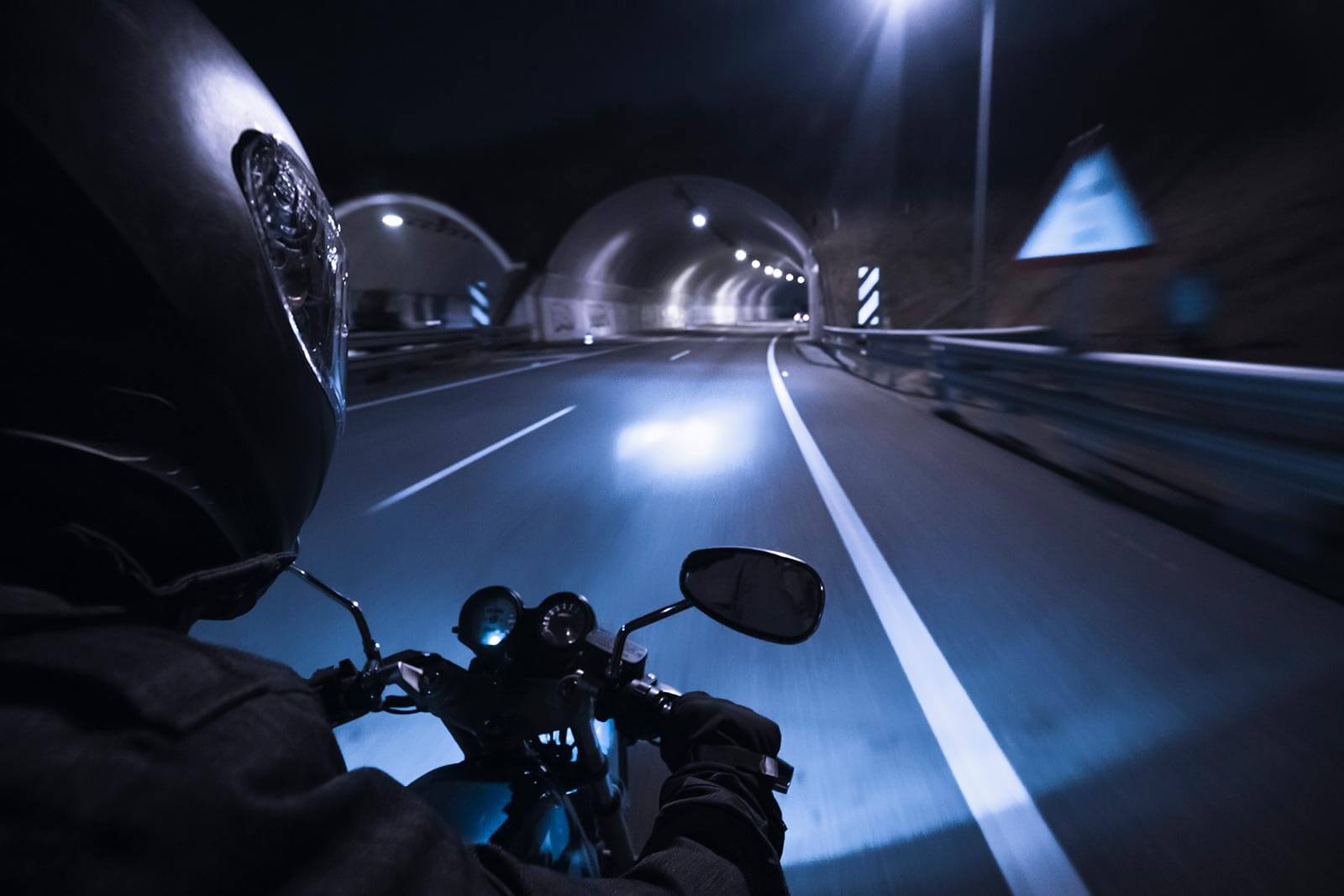Biker on fast bike about to ride through a well lit tunnel